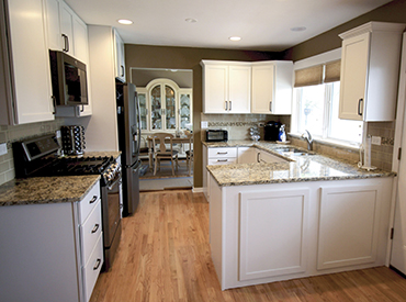 Newly remodeled kitchen with white cabinets, granite counter tops, and custom hardwood flooring