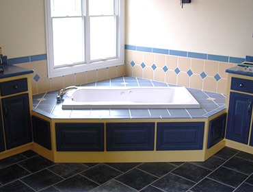 Custom remodeled bathroom with blue tile, drop-in tub with blue tile decking, and dual vanities.